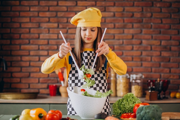 Joven adolescente preparando ensaladas para el desayuno en la cocina