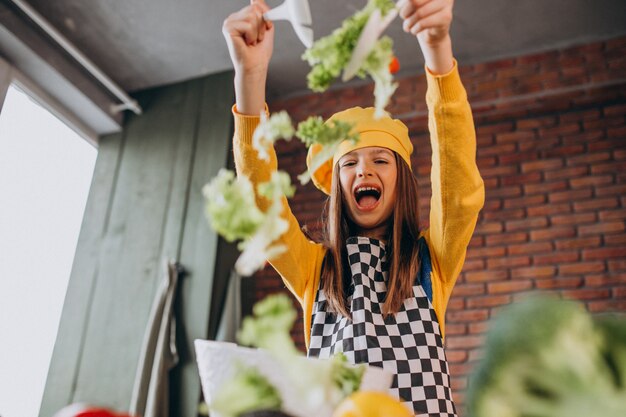 Joven adolescente preparando ensaladas para el desayuno en la cocina