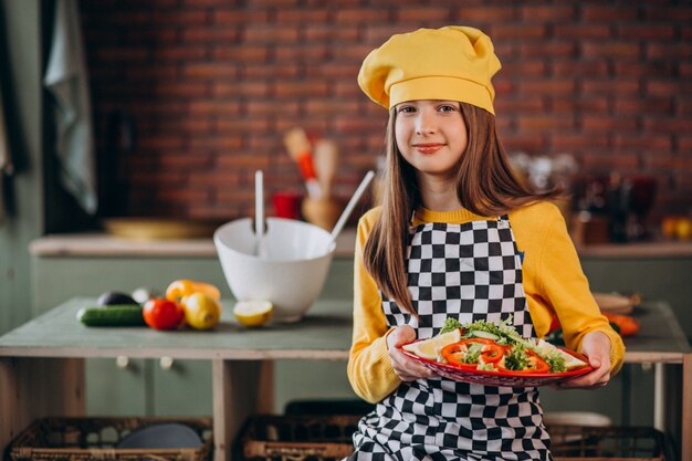 Joven adolescente preparando ensaladas para el desayuno en la cocina