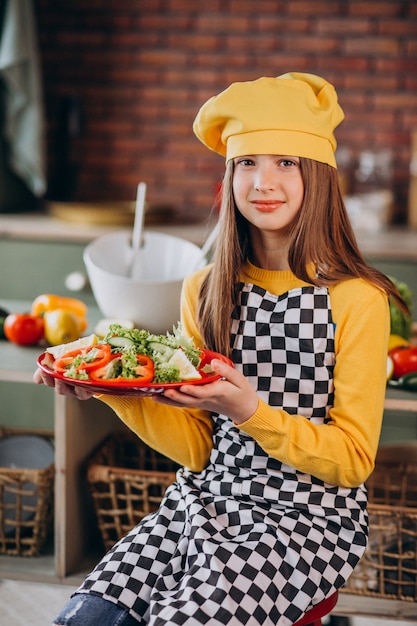 Joven adolescente preparando ensaladas para el desayuno en la cocina