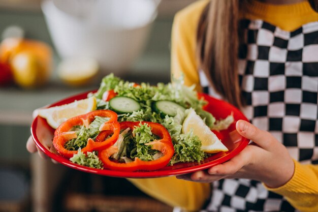 Joven adolescente preparando ensaladas para el desayuno en la cocina