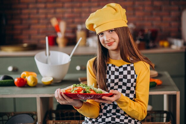 Joven adolescente preparando ensaladas para el desayuno en la cocina