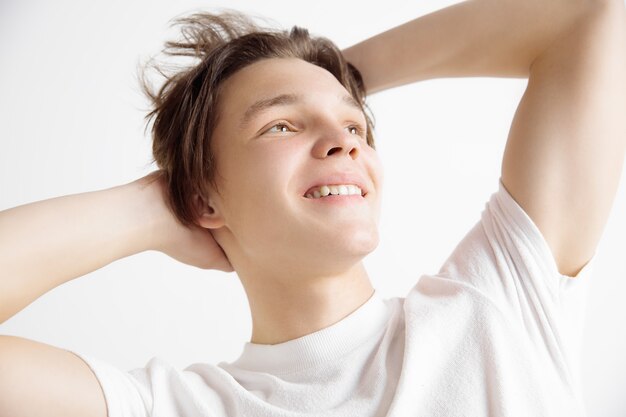 Joven adolescente soñando aislado en blanco mirando algo