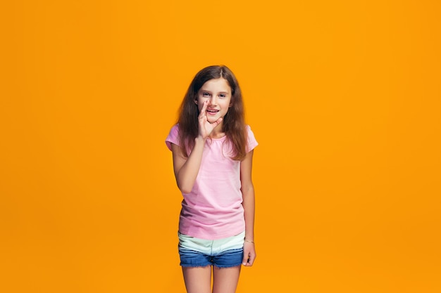 La joven adolescente susurrando un secreto detrás de su mano sobre el espacio naranja