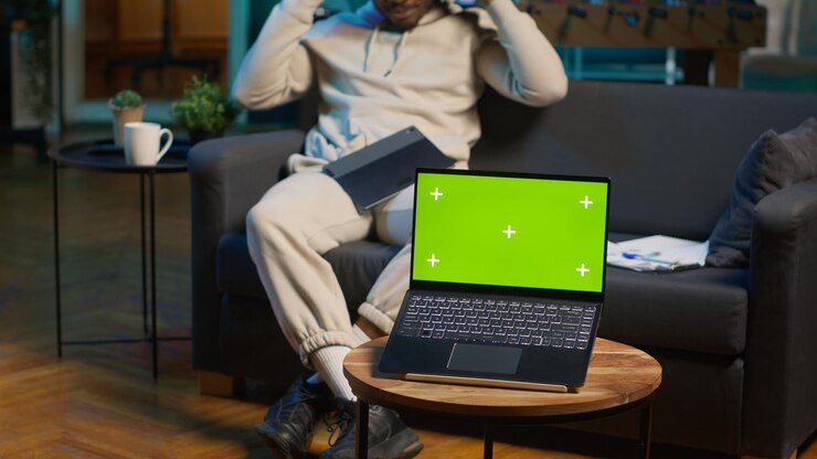 Foto gratuito un joven adulto negro usa una tableta junto a una pantalla verde en su acogedor apartamento moderno.