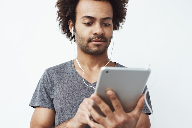 Joven africana en auriculares mirando tableta.