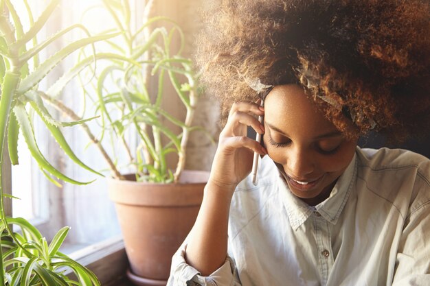 Joven africana con cabello rizado hablando por teléfono