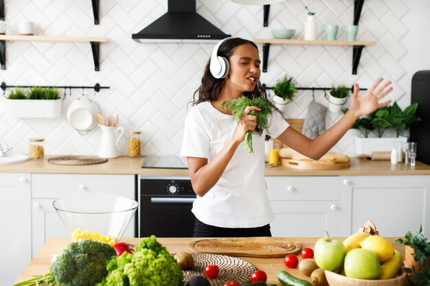 Joven africana emocional está escuchando música a través de auriculares y tiene eneldo