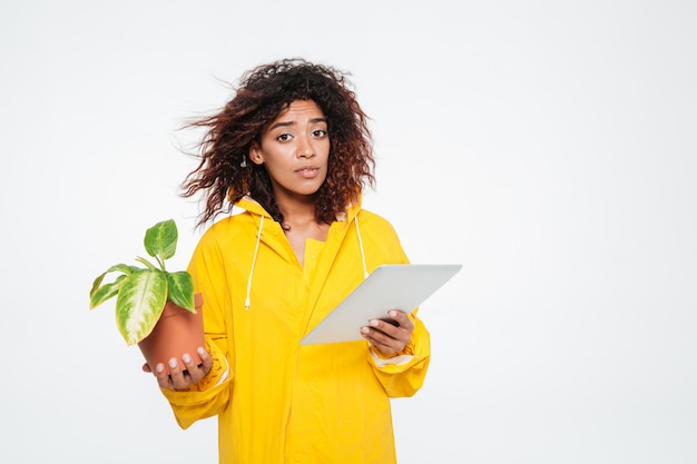 Joven africana en gabardina con planta