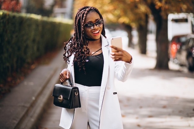 Joven africana en traje blanco con teléfono