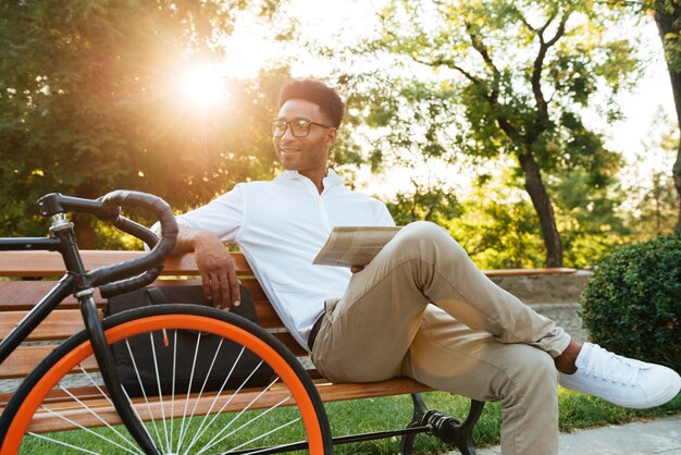 Joven africano concentrado leyendo el periódico.