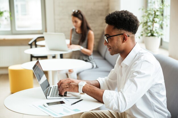 Joven africano concentrado sentado coworking