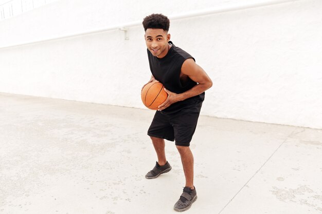 Joven africano jugar baloncesto al aire libre.