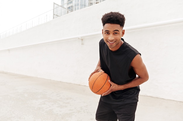 Joven africano jugar baloncesto al aire libre.