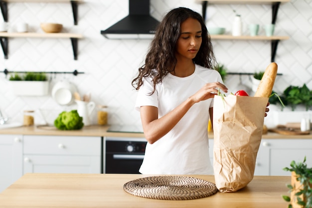 Joven afro va a desempacar productos de una bolsa de papel