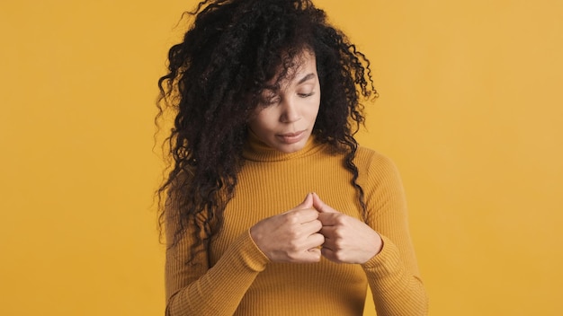Foto gratuita joven afroamericana con cabello oscuro y esponjoso mirando sus uñas pensando en una nueva manicura sobre un fondo colorido