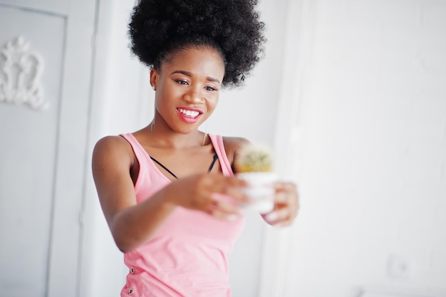 Joven afroamericana en camiseta rosa con cactus en las manos