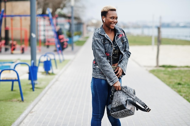 Joven afroamericana milenaria en la ciudad Mujer negra feliz con auriculares inalámbricos Concepto de generación Z