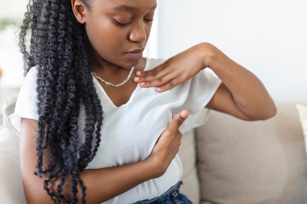 Foto gratuita joven afroamericana palpando su seno por sí misma que le preocupa el cáncer de mama concepto de salud y cáncer de mama