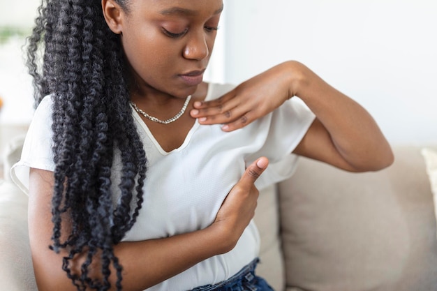 Joven afroamericana palpando su seno por sí misma que le preocupa el cáncer de mama Concepto de salud y cáncer de mama