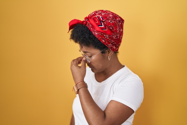 Foto gratuita joven afroamericana parada sobre un fondo amarillo cansada frotándose la nariz y los ojos sintiendo fatiga y dolor de cabeza concepto de estrés y frustración