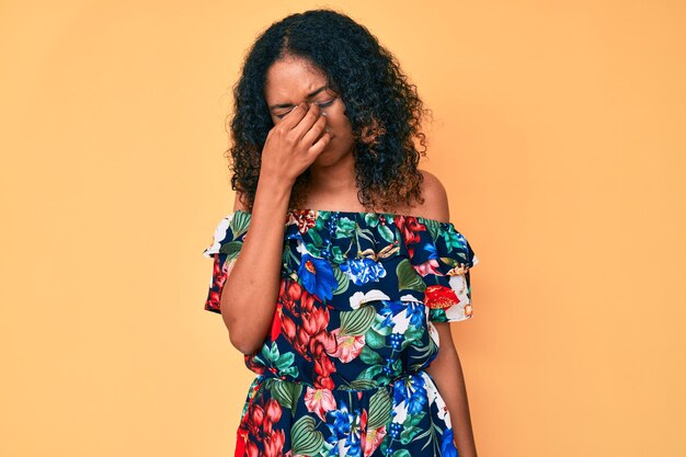 Joven afroamericana con ropa informal cansada frotándose la nariz y los ojos sintiendo fatiga y dolor de cabeza. concepto de estrés y frustración.