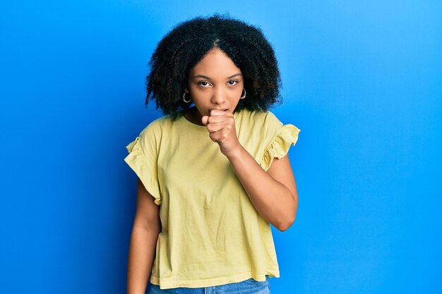 Joven afroamericana con ropa informal sintiéndose mal y tosiendo como síntoma del resfriado o bronquitis concepto de atención médica