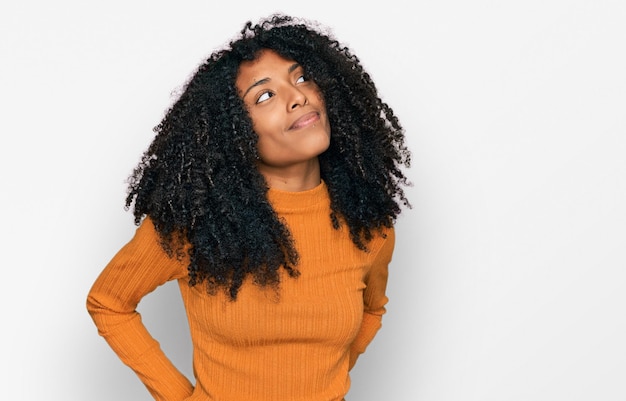 Foto gratuita joven afroamericana con ropa informal sonriendo mirando hacia un lado y mirando hacia otro lado pensando