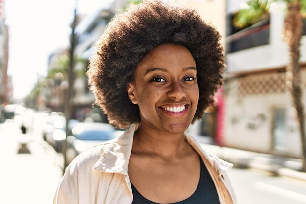 Joven afroamericana sonriendo feliz de pie en la ciudad