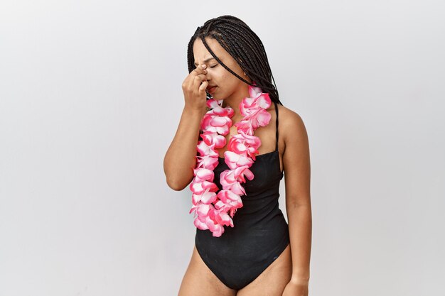 Joven afroamericana con traje de baño y lei hawaiano cansada de frotarse la nariz y los ojos sintiendo fatiga y dolor de cabeza concepto de estrés y frustración