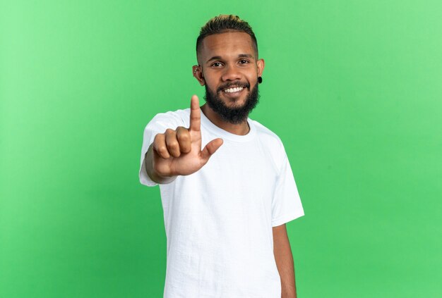 Joven afroamericano en camiseta blanca mirando a cámara con gran sonrisa