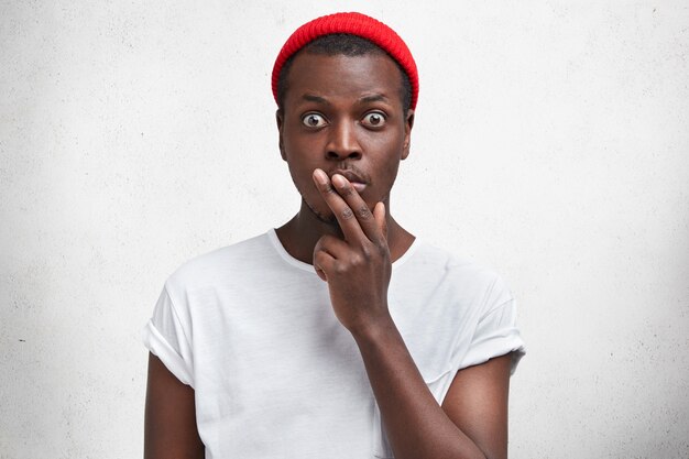 Joven afroamericano en camiseta blanca y sombrero rojo