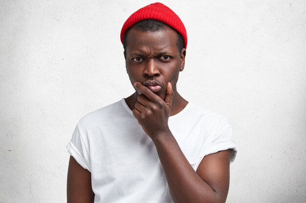 Joven afroamericano en camiseta blanca y sombrero rojo