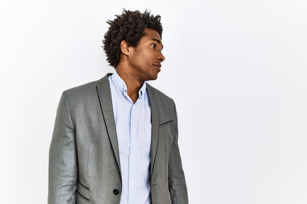 Joven afroamericano con chaqueta de negocios sobre fondo blanco aislado mirando hacia el lado relajado pose de perfil con rostro natural con sonrisa segura