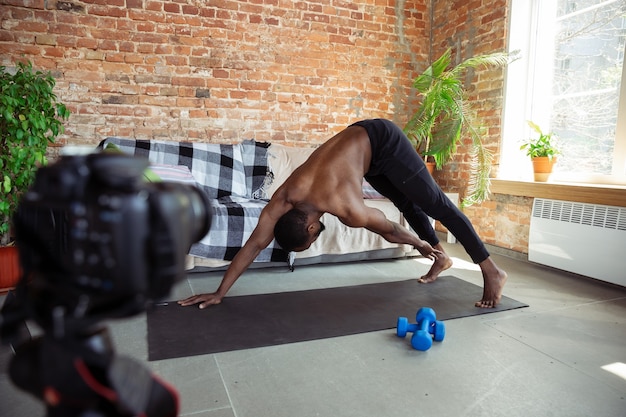 Joven afroamericano enseñando en casa cursos de fitness en línea