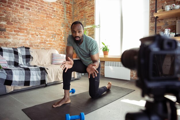 Joven afroamericano enseñando en casa cursos de fitness en línea