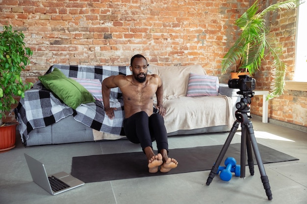 Joven afroamericano enseñando en casa cursos de fitness en línea