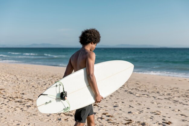 Joven afroamericano macho va a surfear