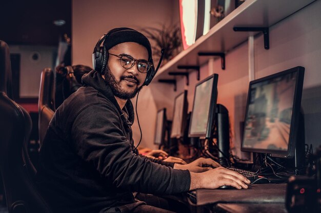 Un joven afroamericano, que disfruta pasar tiempo con sus amigos, jugando en un videojuego multijugador en una PC en un club de juegos o en un cibercafé.