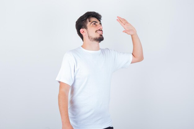 Joven agitando la mano para decir adiós en camiseta y mirando alegre