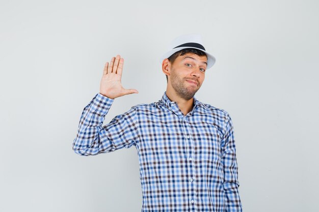 Joven agitando la mano para saludar en camisa a cuadros