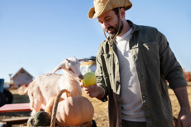 Joven agricultor alimentando a sus cabras con verduras en la granja