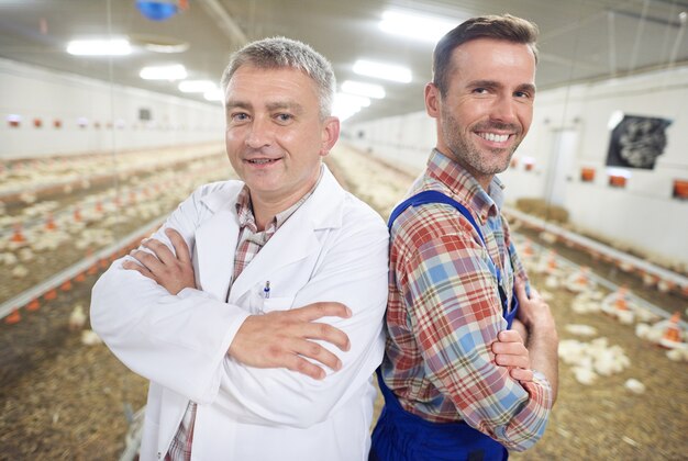 Joven agricultor con médico comprobando la salud de los animales