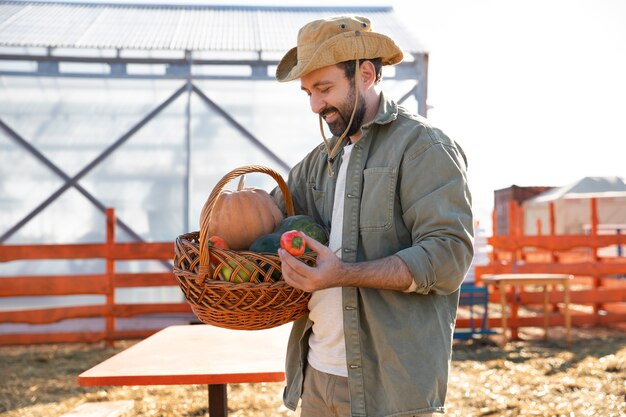 Joven agricultor sosteniendo una canasta con verduras de su granja