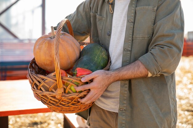 Joven agricultor sosteniendo una canasta con verduras de su granja
