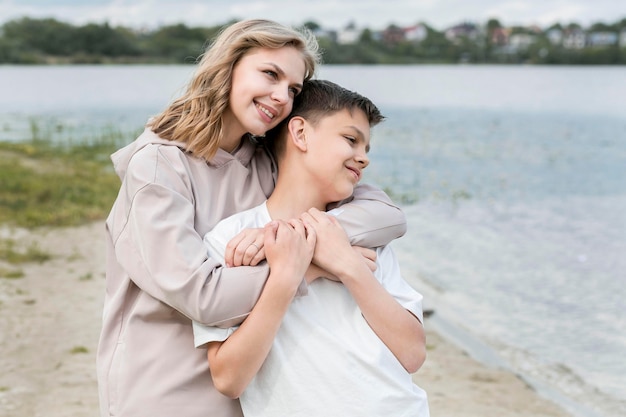 Joven al aire libre y mamá abrazando por el lago