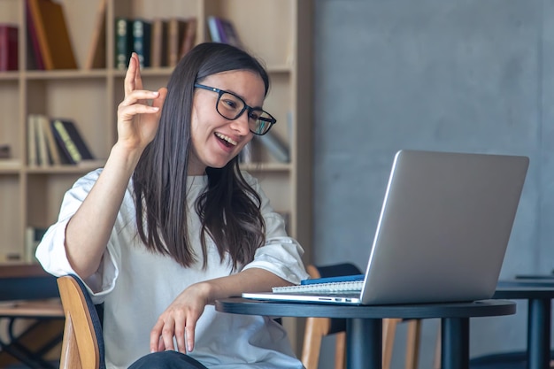 Una joven alegre con gafas frente a una laptop