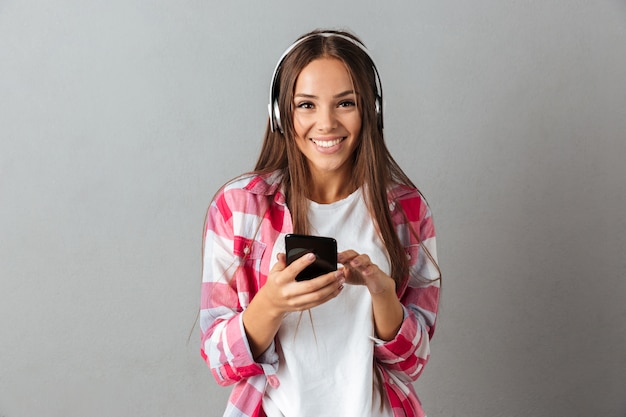 Joven alegre hermosa mujer morena con el pelo largo, escuchando música con auriculares blancos