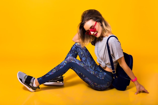 Joven alegre en leggings deportivos y zapatillas de deporte de moda jugando en el estudio