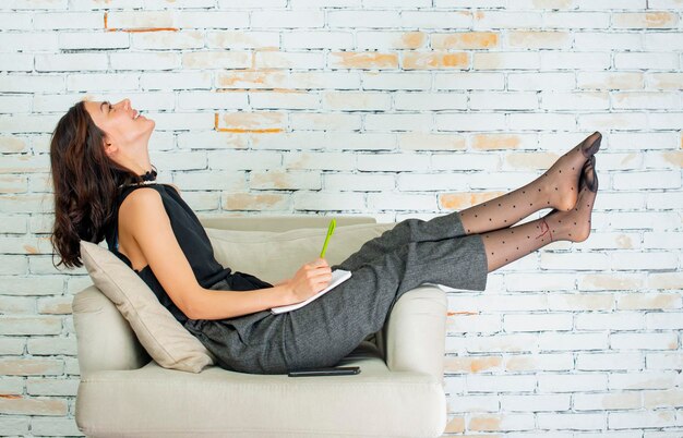 Una joven alegre tumbada en el sillón y sonriendo Foto de alta calidad